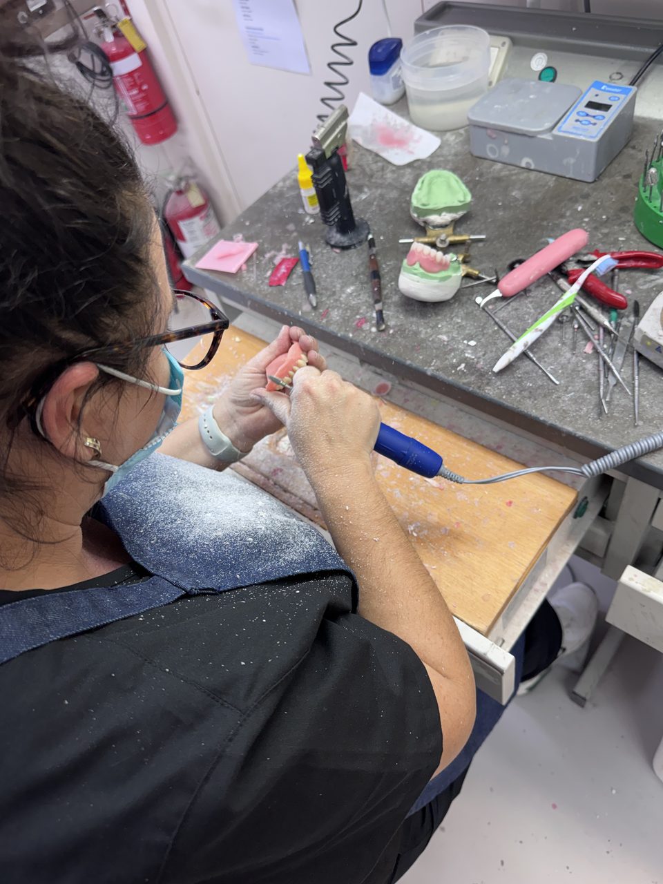 A prosthetist working on a denture case at the laboratory bench